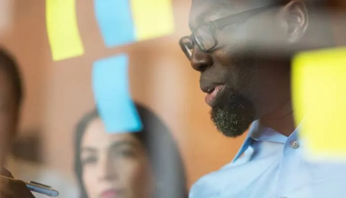Man holding pen and writing a post-it note
